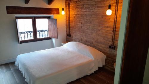 a bedroom with a white bed and a brick wall at Valencia Canyamelar Beach Apartments in Valencia