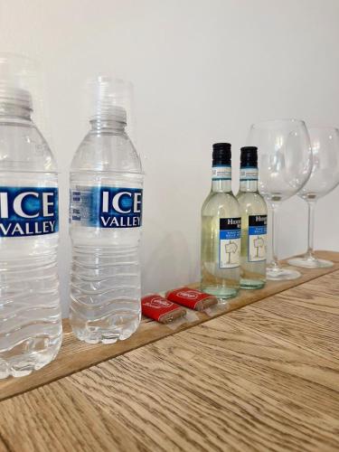 three bottles of water and wine glasses on a wooden shelf at Cambridge Studios and Suites by Tas Accommodations in Cambridge
