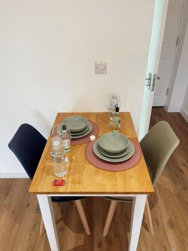 a wooden table with plates and glasses on it at Cambridge Studios and Suites by Tas Accommodations in Cambridge