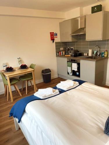 a room with a bed and a table and a kitchen at Cambridge Studios and Suites by Tas Accommodations in Cambridge