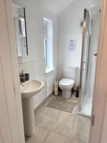 a white bathroom with a toilet and a sink at Cambridge Studios and Suites by Tas Accommodations in Cambridge