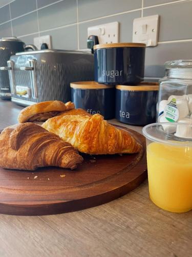 a cutting board with two croissants and a glass of orange juice at Cambridge Studios and Suites by Tas Accommodations in Cambridge
