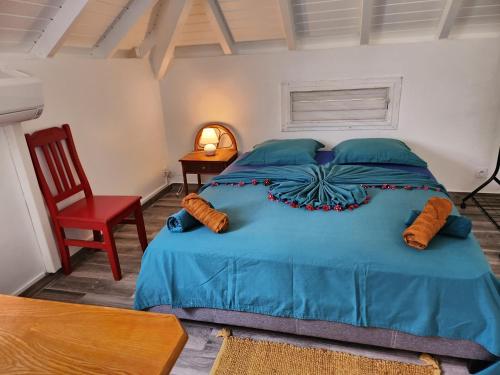een slaapkamer met een blauw bed en een rode stoel bij VILLA 6-10 PERS, VUE MER, Piscine Privée, PLAGE A PIEDS in Le Gosier
