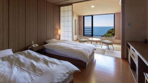 a hotel room with two beds and a balcony at Kyukamura Nanki-Katsuura in Nachikatsuura