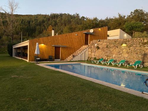 a house with a swimming pool next to a stone wall at Quinta Gerês in Terras de Bouro
