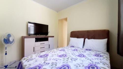 a bedroom with a bed and a flat screen tv at hospedagensjaguariaiva in Jaguariaíva