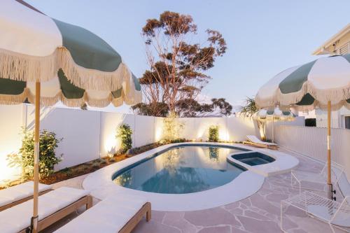 a swimming pool with umbrellas and a house at Motel Molly - Boutique Hotel Mollymook in Mollymook