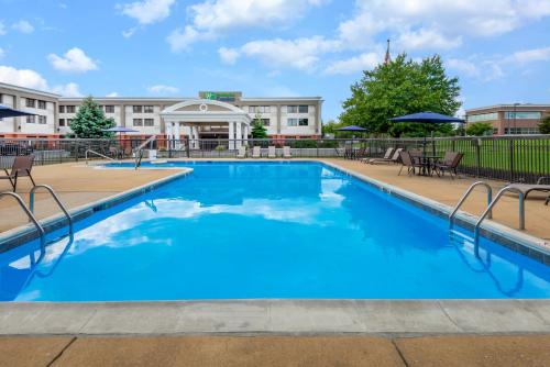 a pool at a hotel with chairs and umbrellas at Holiday Inn Express Philadelphia NE-Bensalem, an IHG Hotel in Bensalem