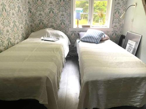 two twin beds in a room with a window at Holiday home ÖDEBORG in Herräng