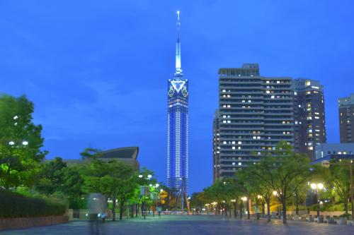 a tall tower with a clock on it in a city at Hotel New Gaea Domemae in Fukuoka