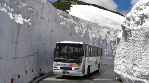 a bus driving down a road in the snow at Kyukamura Norikura-Kogen in Matsumoto