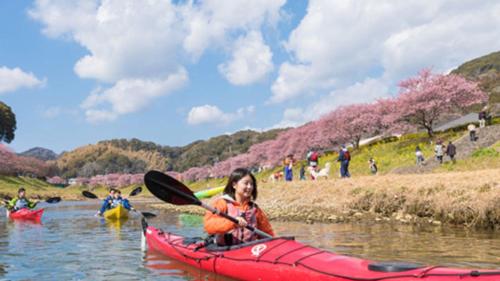 a woman in a red kayak on a river at Kyukamura Minami-Izu in Minamiizu
