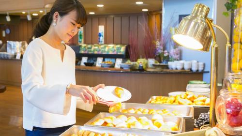 a woman holding a plate of food at a buffet at Kyukamura Minami-Izu in Minamiizu