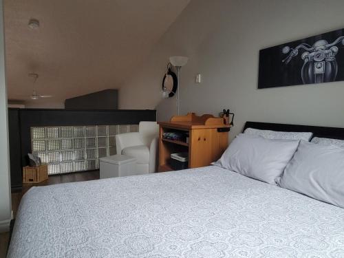 a bedroom with a white bed and a chair at Condo de L'Oberge in Magog-Orford