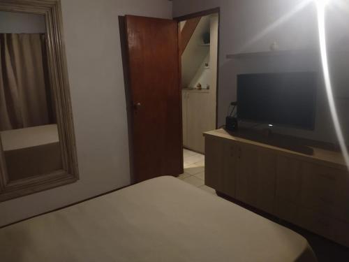 1 dormitorio con 1 cama y TV de pantalla plana en Maria en Villa Gesell