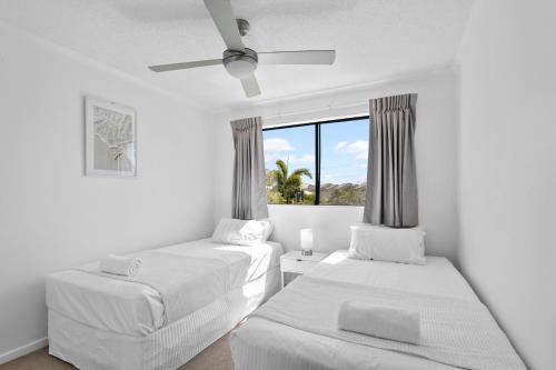 a white room with two beds and a window at Marcoola Beach Resort in Marcoola