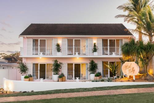 a white house with palm trees in front of it at Motel Molly - Boutique Hotel Mollymook in Mollymook