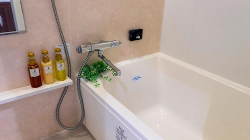a white bath tub with a shower head in a bathroom at Hotel New Gaea Kamigofuku in Fukuoka