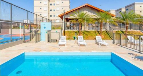 a swimming pool with two lounge chairs next to a building at SOLAR DI LUCCA Lindo Apartamento com piscina in Londrina
