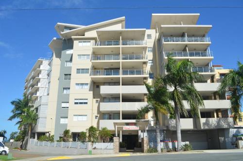 a tall white building with palm trees in front of it at Redvue Holiday Apartments in Redcliffe