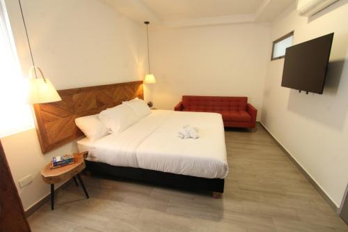 Habitación de hotel con cama y sofá rojo en Hotel Pajara Pinta, en Cali