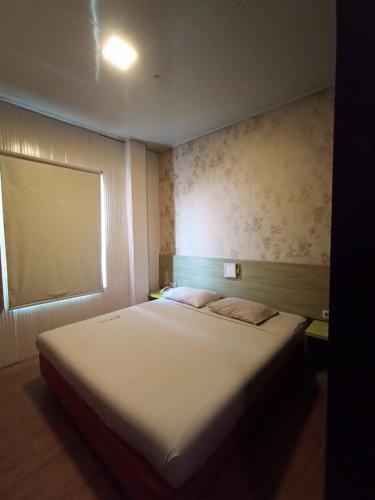 a bedroom with a large white bed with a window at Hotel Aleander in Jakarta