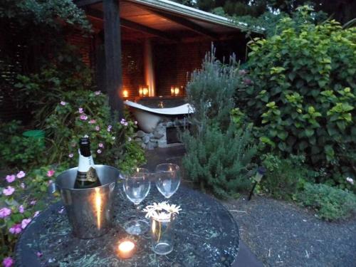 un tavolo con sopra dei bicchieri e una bottiglia di vino di Warm Earth Cottages a Aongatete