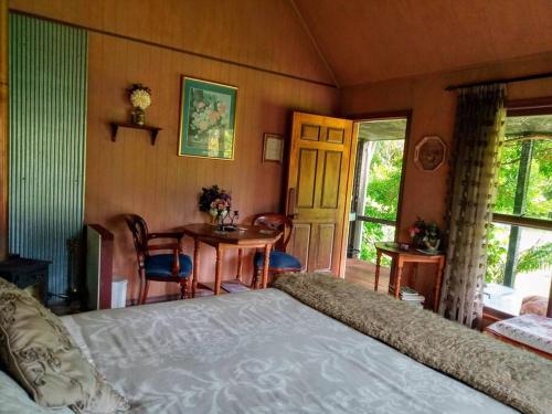 una camera da letto con un letto e un tavolo con sedie di Warm Earth Cottages a Aongatete