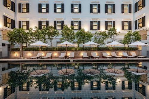 a hotel pool with chairs and umbrellas at Bella Nara Hotel Chiang Mai in Chiang Mai