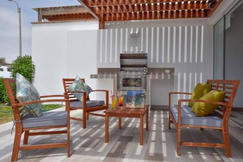 a patio with two chairs and a table and a stove at Casa de playa: Disfruta de grandes momentos y del sol todo el año en Paracas in Paracas