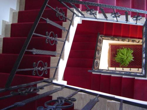 a red stairwell with a mirror and a wreath on it at Hotel Garni Hubertus in Tirolo