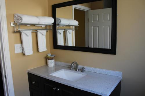 a bathroom with a sink and a mirror and towels at Carmel Wayfarer Inn in Carmel