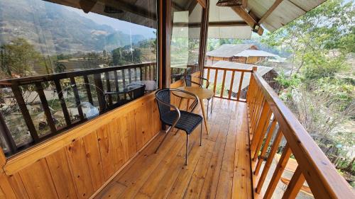 un balcón de madera con 2 sillas y una mesa. en Tavan Dragon House en Lao Cai