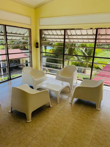 a room with white chairs and tables and windows at Hotel Al Mare in Santa Cruz de Barahona
