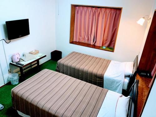 Habitación de hotel con 2 camas y escritorio con ordenador en Hotel Harbor, en Agena
