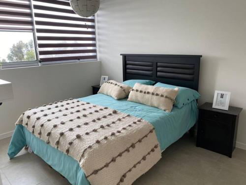 1 dormitorio con 1 cama con edredón azul y ventana en Arriendo Departamento Nuevo, Algarrobo Norte, en Algarrobo