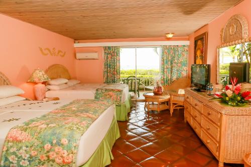 a hotel room with two beds and a television at Coco Reef Resort & Spa in Crown Point