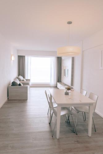 a white dining room with a white table and chairs at Pinamar Beach Resort in Pinamar
