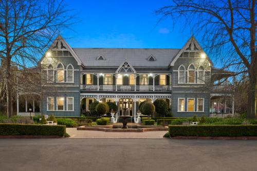 una casa grande con luces que iluminan la parte delantera de ella en The Convent Hunter Valley Hotel, en Pokolbin