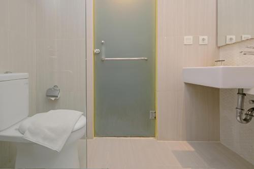 La salle de bains est pourvue d'une porte de douche en verre à côté d'un lavabo. dans l'établissement KHAS Semarang Hotel, à Semarang