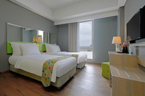 a hotel room with two beds and a flat screen tv at KHAS Semarang Hotel in Semarang