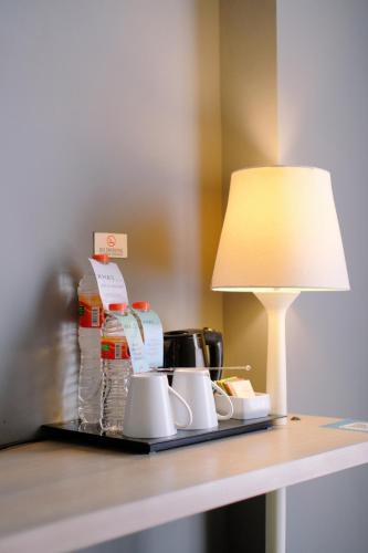 a table with a lamp and mugs on it at KHAS Semarang Hotel in Semarang