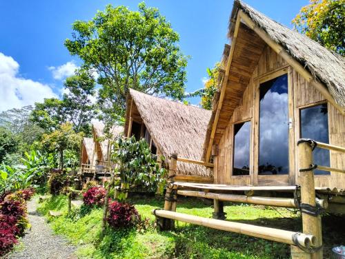 a wooden house with a thatched roof at Wanagiri Campsite in Gitgit