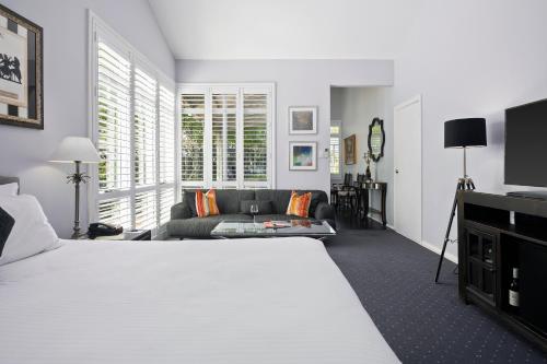 Un dormitorio con una gran cama blanca y un sofá. en The Convent Hunter Valley Hotel, en Pokolbin