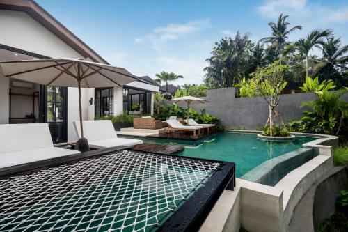 a pool in a backyard with two chairs and an umbrella at Villa Hammock by BaliSuperHost in Ubud