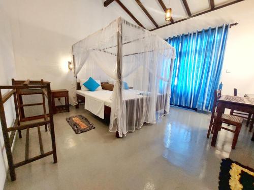 a bedroom with a bed with a mosquito net at Sweden Inn Guesthouse in Hikkaduwa