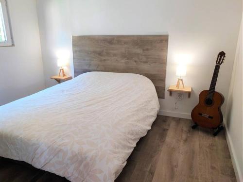 a bedroom with a white bed and a guitar at Maison T2 proche mer jardin et parking securise in Six-Fours-les-Plages