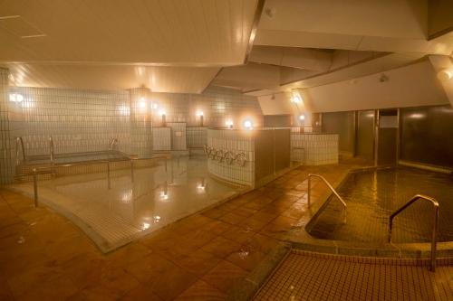 an empty swimming pool in a building with lights at KAMENOI HOTEL Kujukuri in Asahi