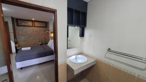 a bathroom with a bed and a sink in a room at Sandat Hotel Legian in Legian