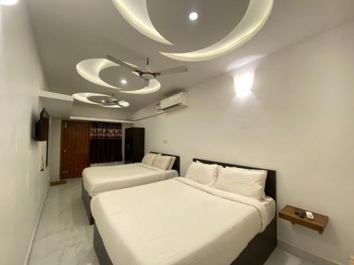 1 dormitorio con 2 camas y ventilador de techo en La Paradise Luxury en Pondicherry